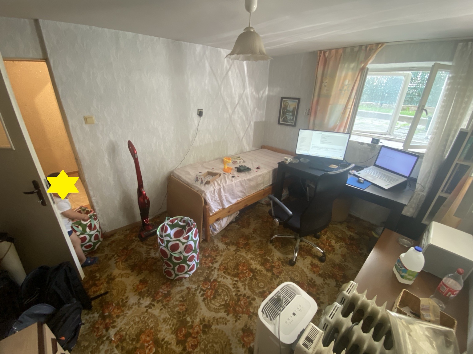 Early founder workspace with desk, laptop, monitor, and bed